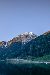View of the calm waters of the lake of Poschiavo in Switzerland early in the morning