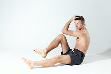 Fototapeta na wymiar athletic guy in shorts doing exercises in a bright room bodybuilder fitness