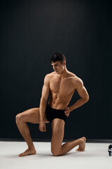 Obraz premium athletic man with a pumped-up body is kneeling in dark Studio panties