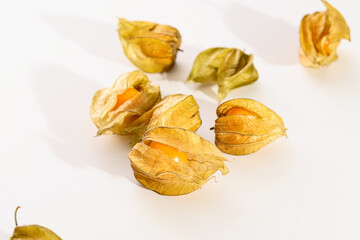 bright juicy yellow physalis berries scattered on a white background