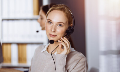 Businesswoman talking by headset in office. Call center and diverse people group in business