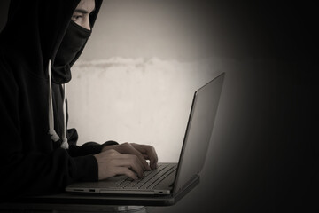 Anonymous hacker with stealing data from laptop. Cyber security concept.