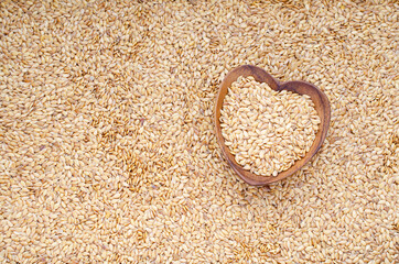 Dry organnic golden flax seed in heart shape wooden box