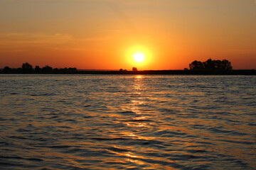 Fototapeta premium beautiful sunset by the river with waves