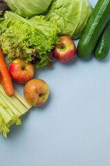 layout of vegetables on blue background: carrots, celery, cucumbers, zucchini, apples, cabbage, lettuce.  Concept of healthy eating. Vegan and vegetarian concept. Top view, place for text