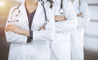 Doctors standing as a team with arms crossed in sunny clinic. Medical help, insurance and medicine concept