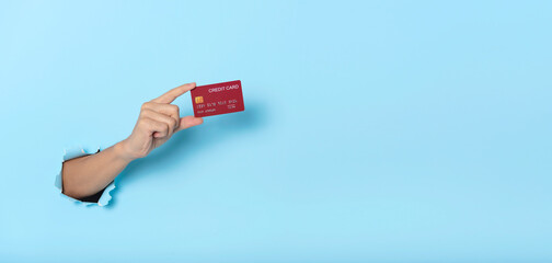 Woman hand holding credit card on blue banner background. Panoramic image