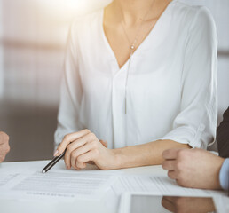 Elderly businessman and group of business people discussing contract in sunny office, close-up
