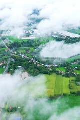 Aerial view a village and rice paddy fields in rainy season.
