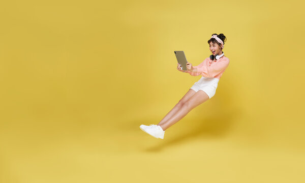 Young asian teenage girl hand holding computer laptop floating in mid-air isolated on yellow background. Fast internet concept.