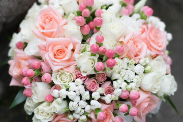 Beautiful bridal bouquet of white flowers and greenery, on a gray textural background. Top view.