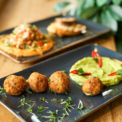 chickpea hummus and guacamole and falafel dish on blue plate on a wooden table.