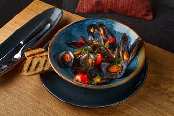Delicious seafood mussels with with sauce and parsley. Lemon and baguette . Clams in the shells.