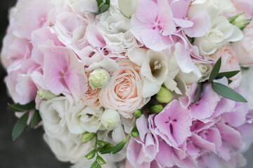 Beautiful bridal bouquet of white and pink flowers and greenery, on a gray textural background. Hydrangea wedding bouquet.