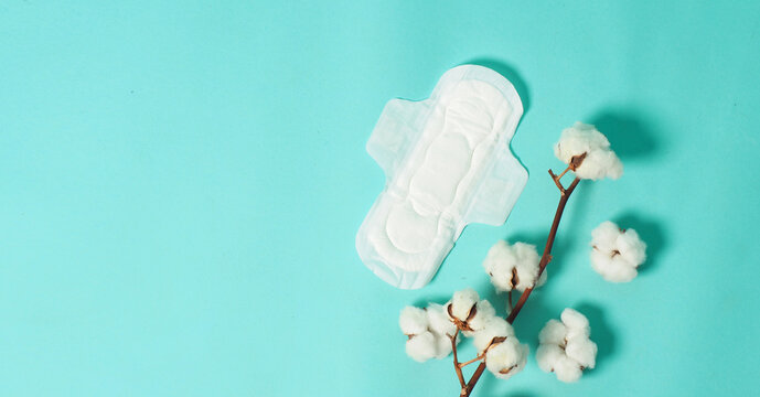Sanitary napkin with wings and cotton flowers on mint green color or Tiffany Blue background.top angle view