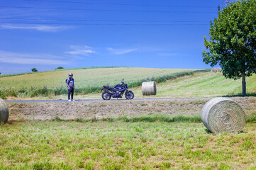 moto biker on a rural sun-drenched agricultural fields with haystacks