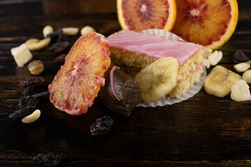 two cakes in pink frosting with a scattering of dried fruits with three slices of red orange