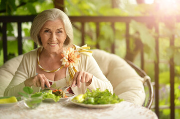 Portrait of happy senior woman eating delicious salad