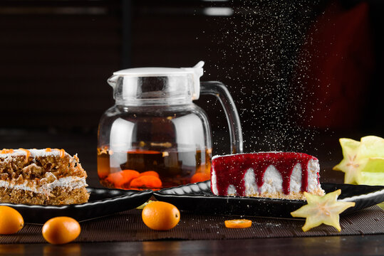 Cheesecake with berry sauce and carrot cake with sour cream and caramel on black square plates on dark wooden table