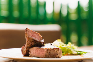 Steak on white plate on the background of the restaurant. Medium-rare juicy meat