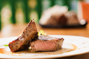 Steak on white plate on the background of the restaurant. Medium-rare juicy meat