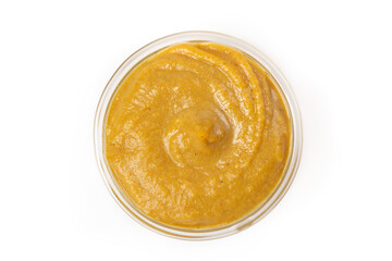 Mustard yellow sauce in a transparent bowl isolated on a white background. Top view.