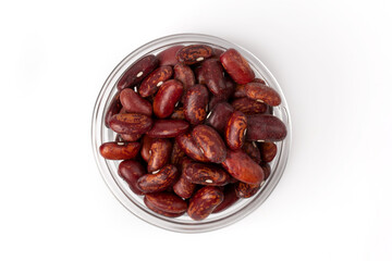 A pile of fresh raw red beans in a transparent bowl, isolated on a white background, top view.
