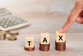 Wooden cubes with the word Tax on money climbing staits, pile of coins ,Tax Concept background.