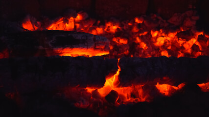 Smoldering embers on dark background. Fire safety concept. Burned out bonfire during night camping. Blurred image.
