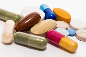 Close-up colorful assorted soft capsules pill vitamin tablet blue pink yellow brown supplements on white background