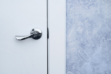 Metal handle on white closed door in an indoor room.