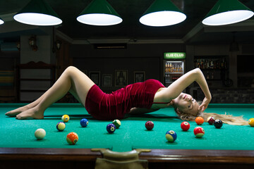 sexy blonde girl lies on a billiard table