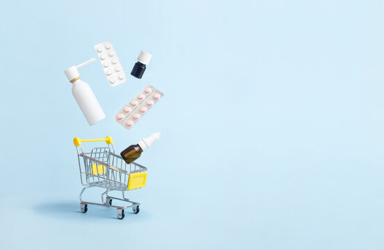 Medicines and pills levitation in a shopping cart on blue background. Drug delivery. Copy space. Creative medical concept