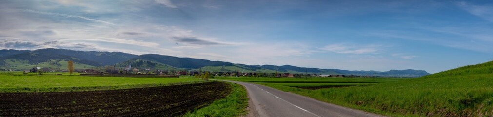 Fototapeta na wymiar Panoramic view, asphalt road leading to a small hungarian village at springtime.