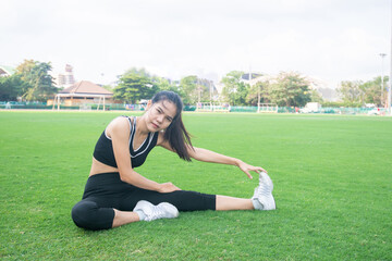 Portrait of beautiful young woman exercising on green grass. female fitness model stretching exercise or warming up before work out. exercise, Fitness, workout, sport, lifestyle concept.