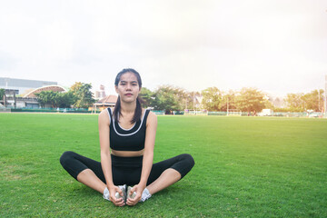 Fototapeta premium Portrait of beautiful young woman exercising on green grass. female fitness model stretching exercise or warming up before work out. exercise, Fitness, workout, sport, lifestyle concept.
