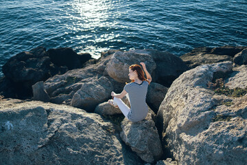 woman in full growth sits on stones on the beach near the sea top view
