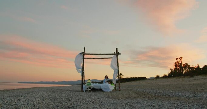 Ragazza con letto baldacchino in spiaggia vicino al mare
