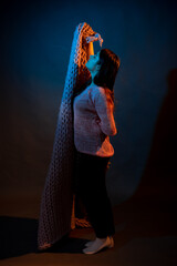 The girl dances with a pink plaid in her hands. illuminated by yellow and blue light