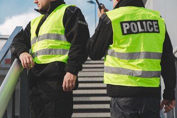 Policemen in reflective vests looking around carefully during patrol in the city center