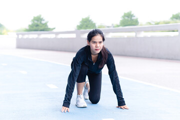 Young Beautiful Asian Woman black suit getting ready to start on running track. exercise, fitness, workout, sport, lifestyle concept. Goal of business. Forward to Success concept. Copy space.