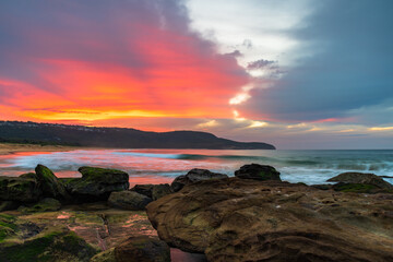 Soft high cloud sunrise seascape with green mossy rocks