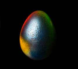 Multi-colored easter egg on a black background. Handwritten inscription, happy easter