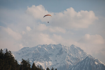 The paraglider is flying in the sky. Against the background of the mountains. Alps
