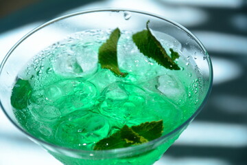 Glass of cocktail green fairy with lemon and mint leaves. Sweet refreshing mint liqueur, with ice and absinthe, rum, Ice cubes and Vodka