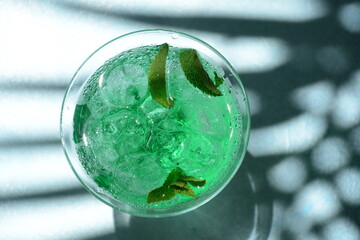 Glass of cocktail green fairy with lemon and mint leaves. Sweet refreshing mint liqueur, with ice and absinthe, rum, Ice cubes and Vodka