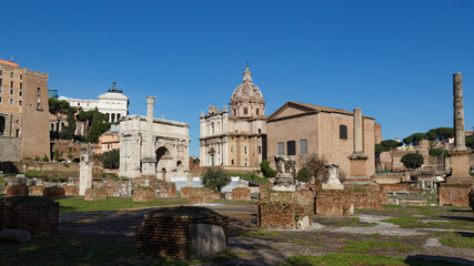 Fototapeta na wymiar Ruins of the Roman Forum. View of the Basilica Julia with Santi Luca e Martin in the background