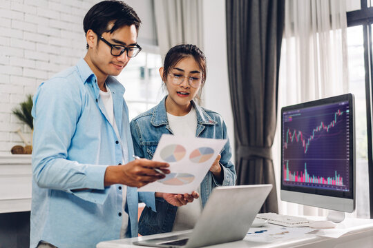 Successful of business trader asian couple use technology of computer trading graph of block chain stock market cryptocurrency investment selling and buying with price chart data graph at home - Powered by Adobe
