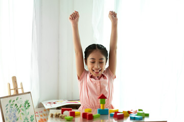 Portrait of enjoy happy asian little asian girl smiling playing with toy build wooden block board game at home
