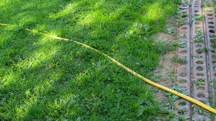 yellow hose for watering the garden against a background of green grass